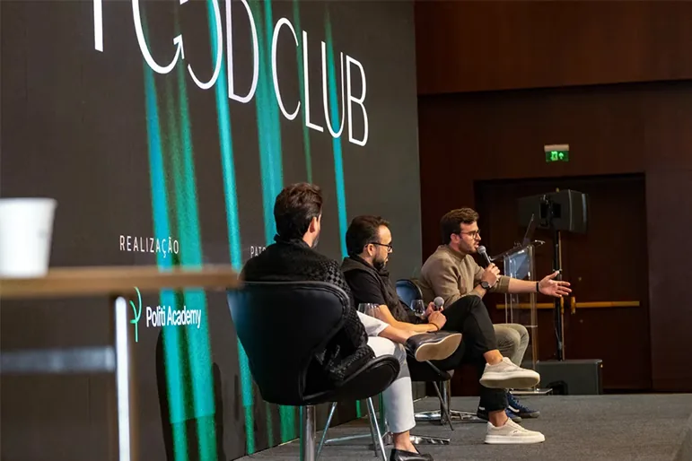 Painel de discussão com três participantes no palco